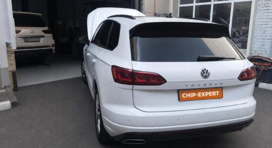 Белый Volkswagen Touareg 3.0TDI 2019 с открытым капотом, вид сзади слева у въезда в ремонтную зону мастерской Чип-Эксперт — chip-expert.pro.
