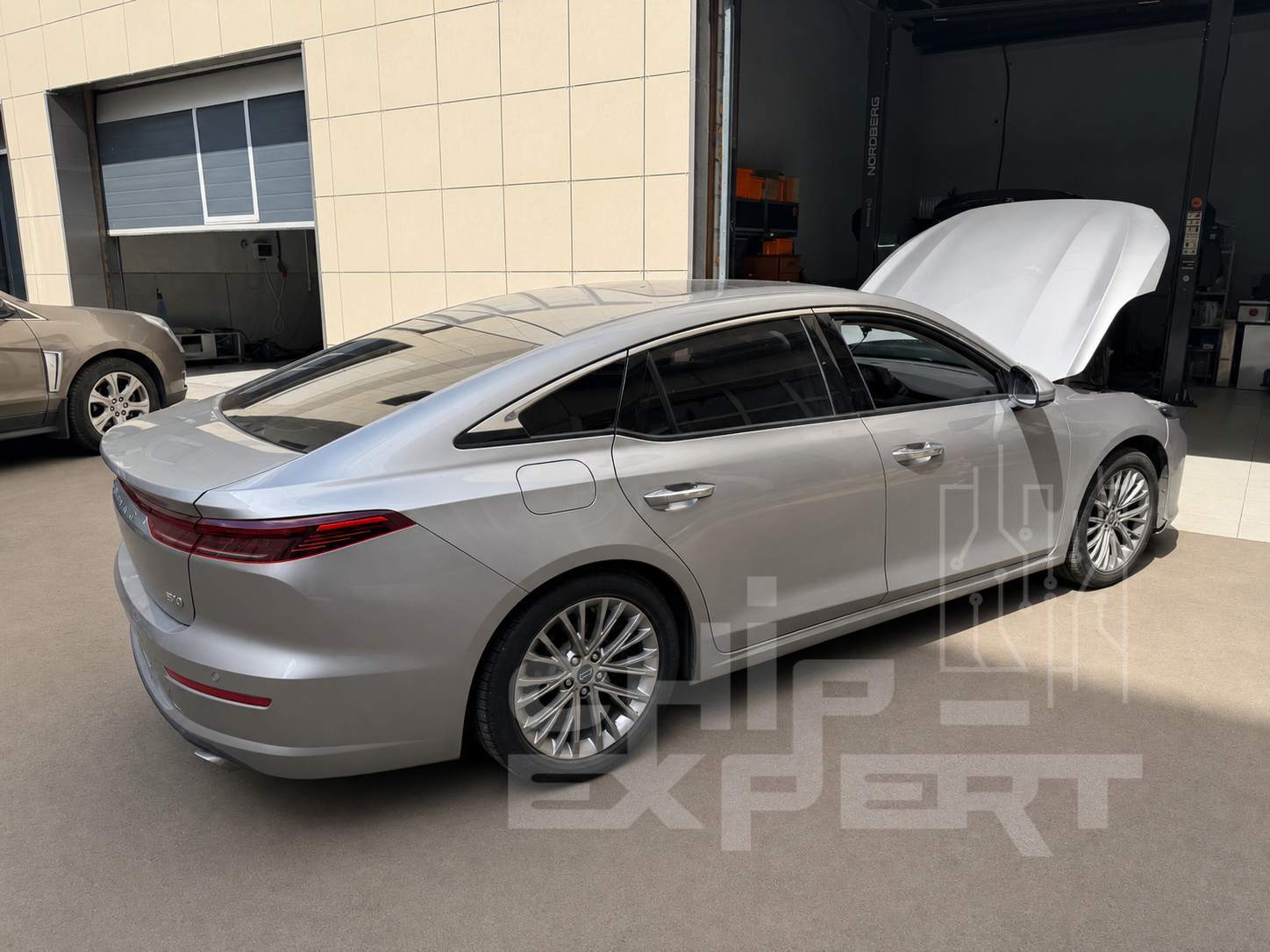 Серебристый Bestune B70 2.0T 2024 с открытым капотом, вид сзади слева у въезда в мастерскую Чип-Эксперт — chip-expert.pro.