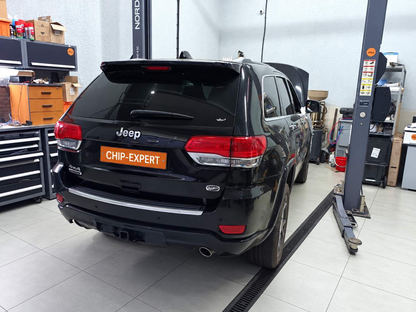 Jeep Grand Cherokee 3.0D 2019: вид автомобиля сзади справа в ремонтном боксе. Чип-Эксперт — chip-expert.pro.
